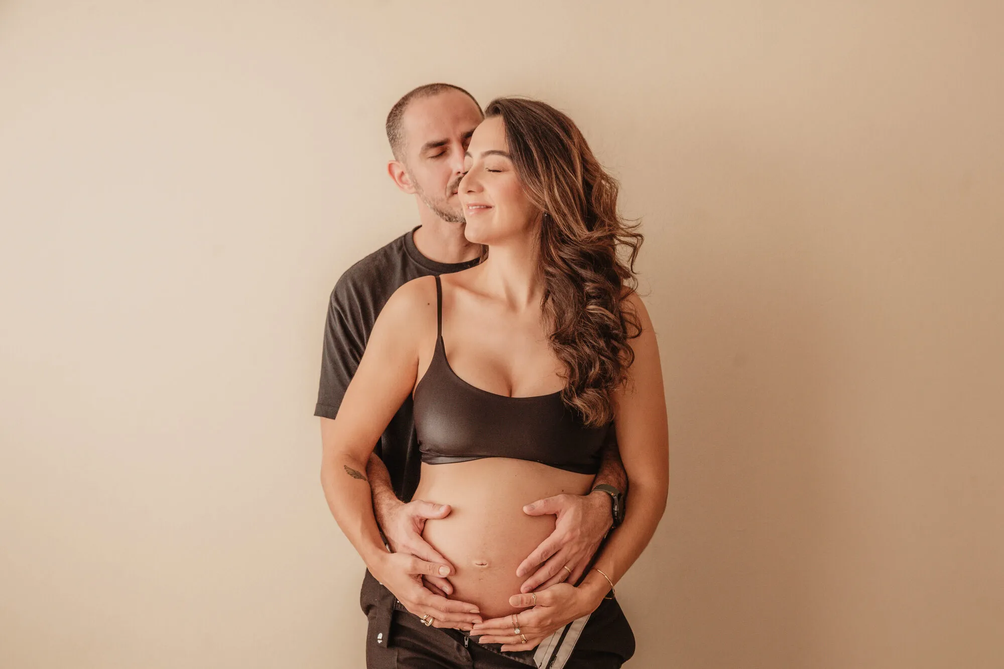Casal grávido trocando carinho, o pai beijando a testa da mãe