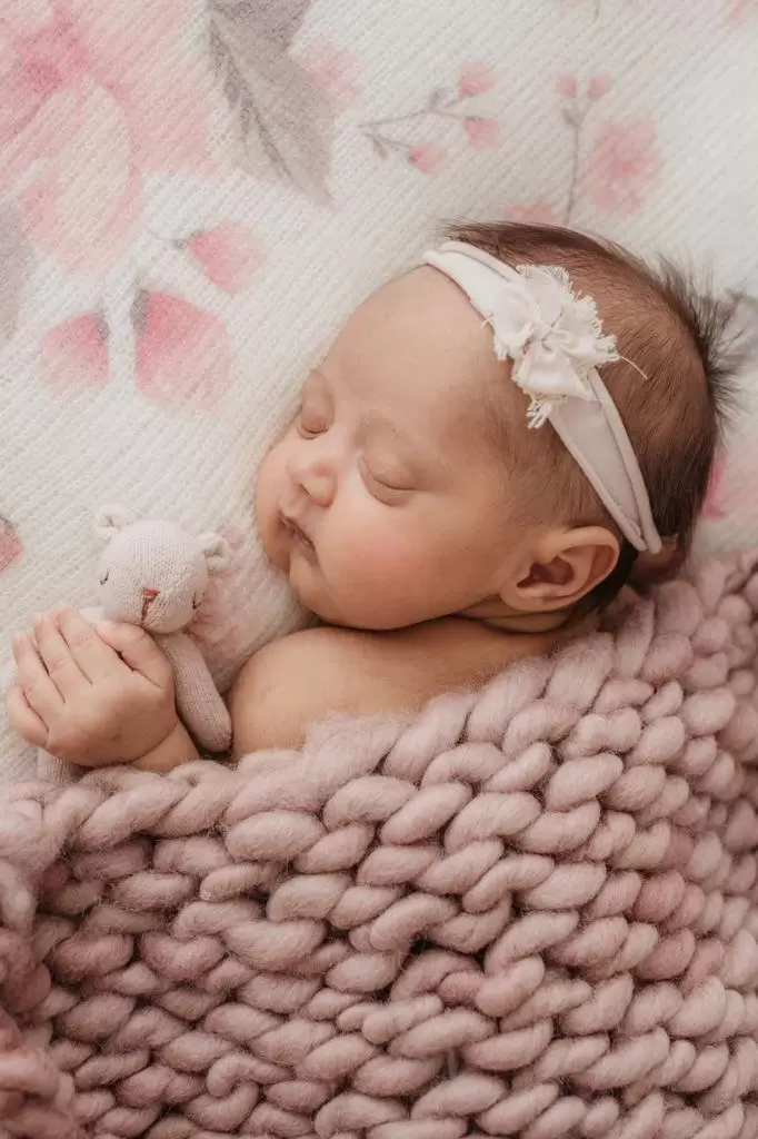 Detalhe delicado de recém-nascida enrolada em wrap com headband